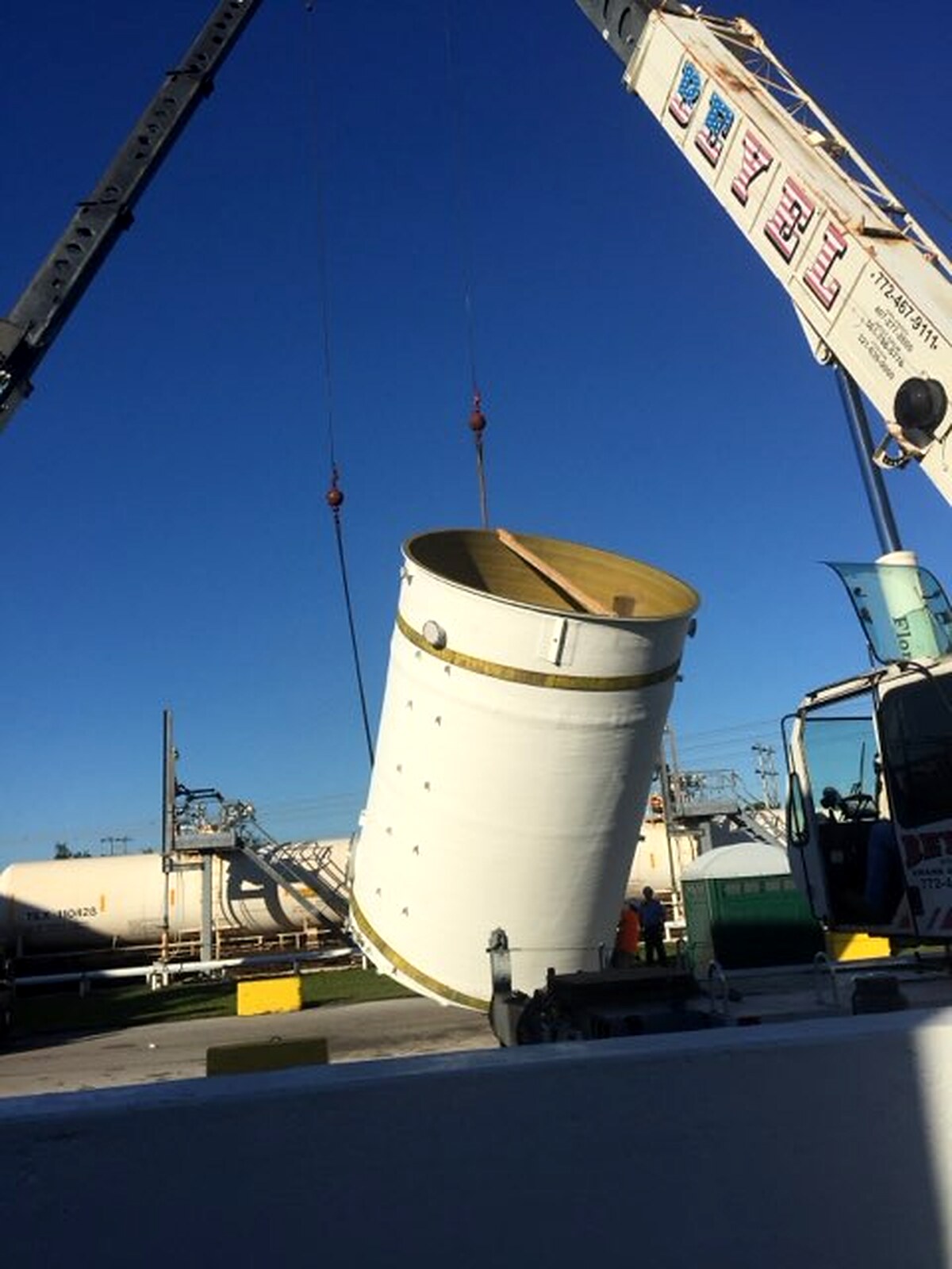 Crane lifting a fiberglass tank into position